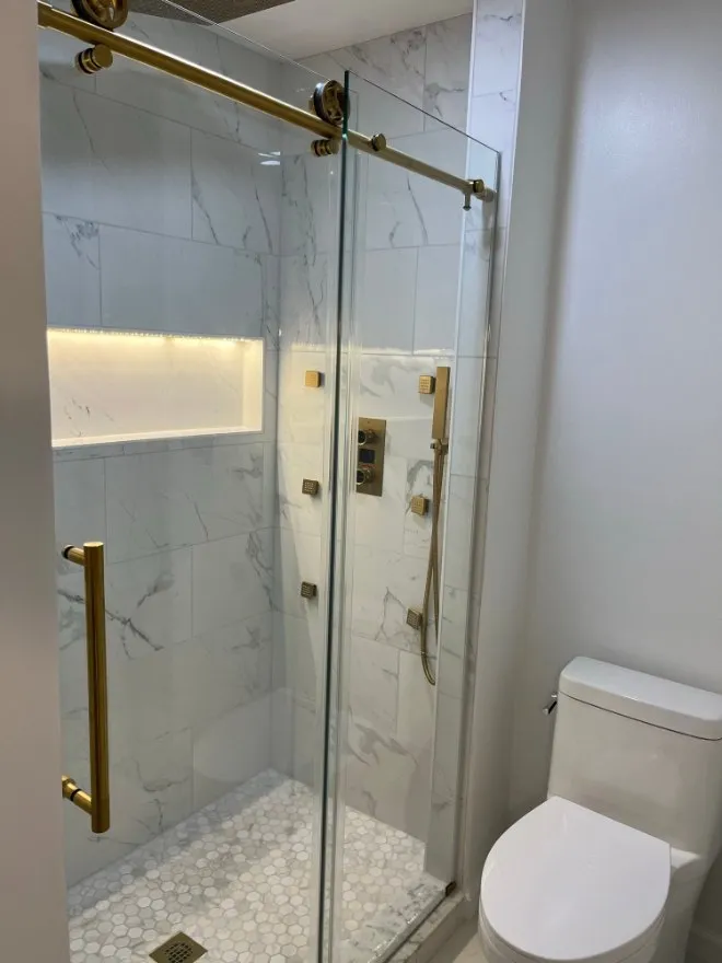 Finished walk-in shower with gold fixtures and a hex tile floor