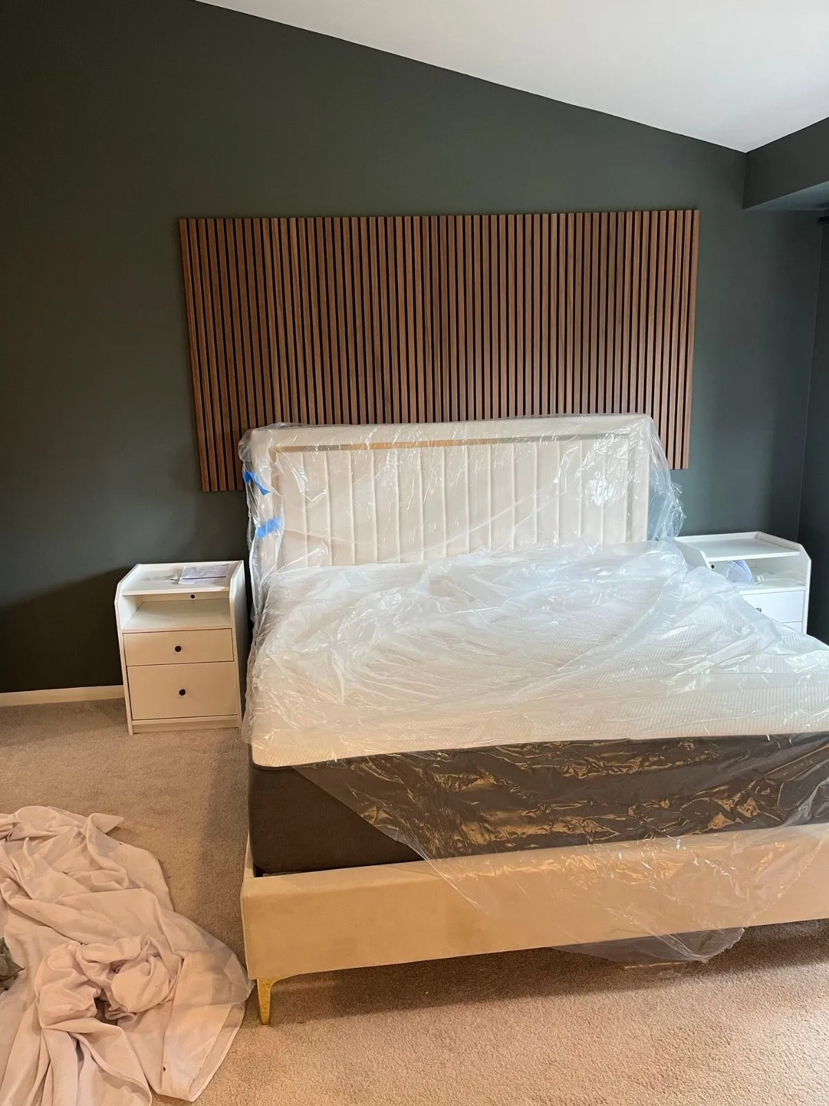 Wood-slat acoustic accent wall installed behind the bed