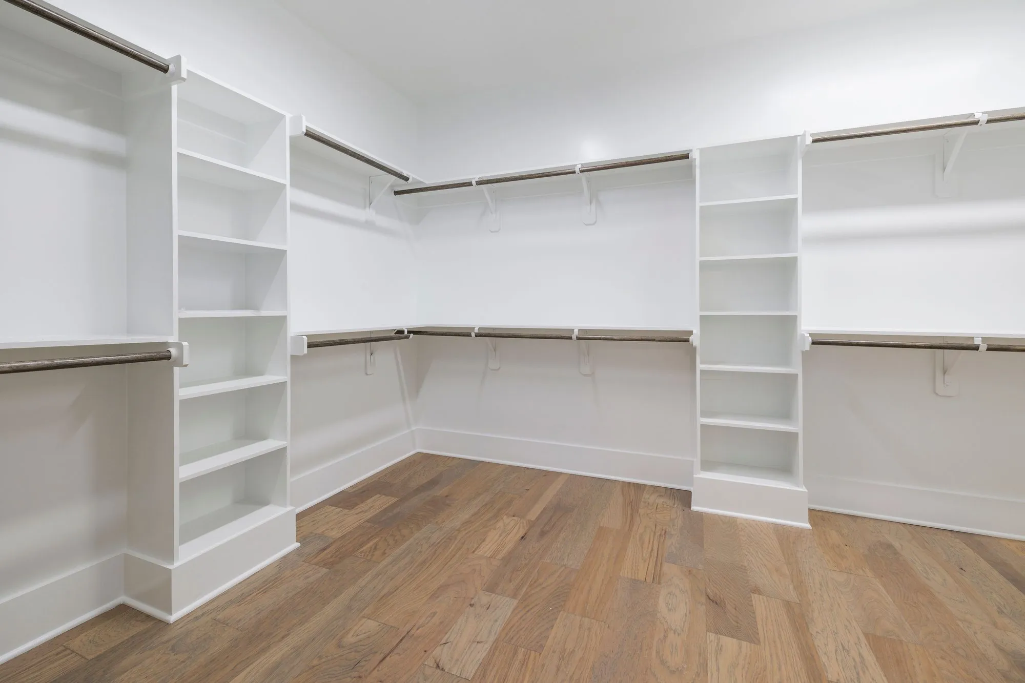 Empty walk-in closet with white shelving towers and hanging rods