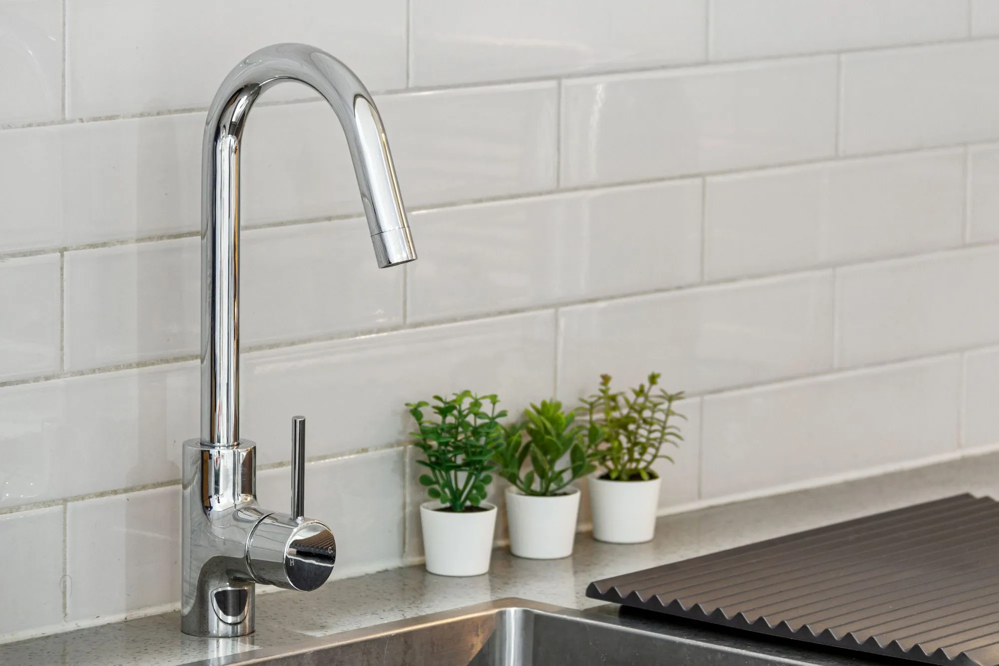 Chrome kitchen faucet against white subway tile